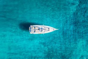 Top down Ansicht eines Segelbootes über dem türkisem Meer der Ägäis in Griechenland